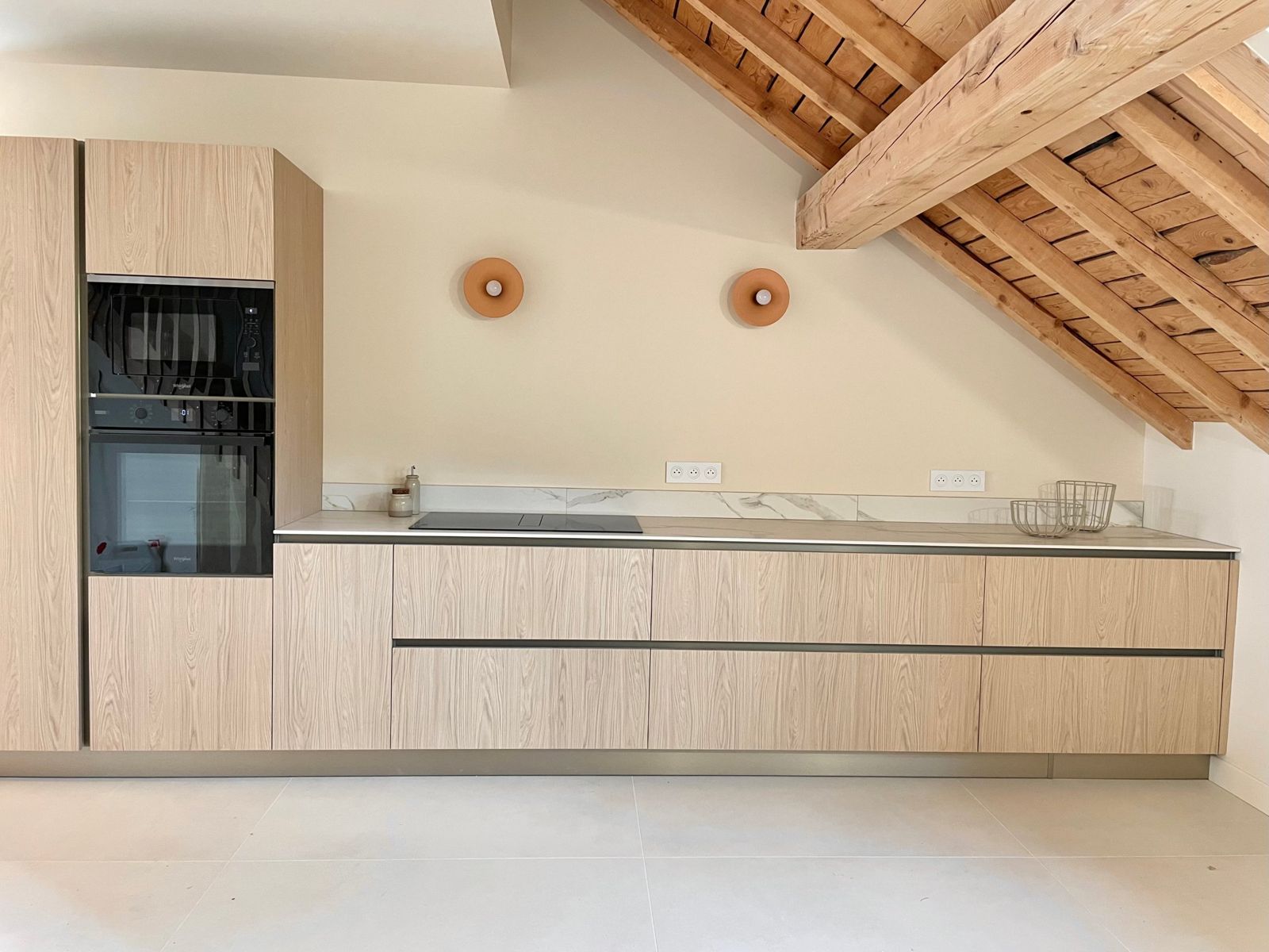 La cuisine équipée en bois clair, sous la charpente